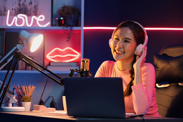 Smiling creative young beautiful Asian influencer talking in channel with positive podcast speech...