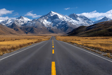 Fototapeta premium Endless asphalt road leading to majestic snow capped mountains under a bright blue sky yellow lines