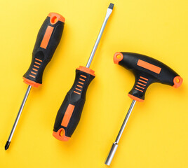 Screwdrivers and bit holder set on bright yellow background top view flat layout