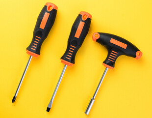 Screwdrivers and bit holder set on bright yellow background top view flat layout