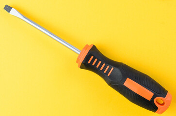 Flathead screwdriver single metal hand tool isolated on bright yellow background top view