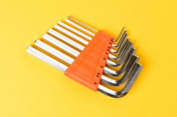 Set of hex keys arranged on bright yellow background metal allen wrenches top view