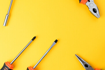 Empty center space with screwdriver flathead philips pliers on both sides yellow background