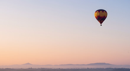 Obraz premium A single hot air balloon floating in the upper right third of a clear morning sky.