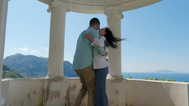 Romantic couple dance on pavilion terrace in Capri island, enjoying coastal views and summer breeze