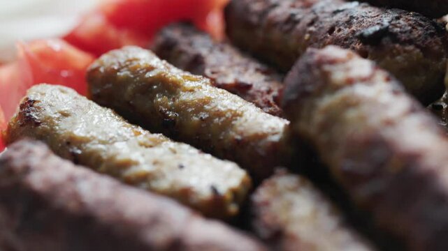 A balkan traditional meatball dish cevapi, cevapcici on wooden table in close-up