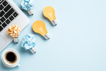 Creative workspace with colorful paper light bulbs and coffee cup beside laptop, symbolizing innovation and ideas. arrangement inspires productivity and creativity