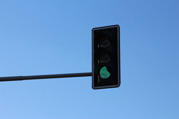 Green traffic light signal against clear blue sky showing go signal and urban transportation infrastructure