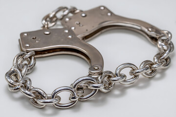 Fototapeta premium Polished metal handcuffs connected by a thick chain silver linked