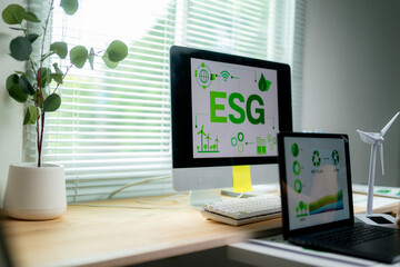 Desktop and laptop displaying ESG graphics in a bright workspace