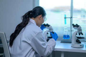 Scientist examining samples under microscopes in a lab setting