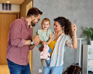 Portrait of mother, father and daughter having fun dancing at home, family life, parenting, love and bonding concepts