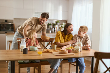 Happy father serving food to his family at dining table.