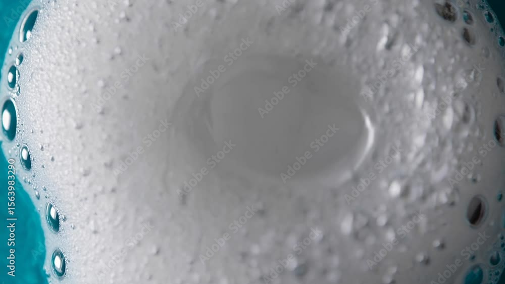 Poster foamy white surface gradually dissolving, creating expanding hole and revealing vivid turquoise back