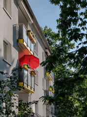 Sommerhitze, Balkon am Haus mit roten Sonnenschirm