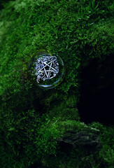 pentagram amulet on dark moss texture natural background. witch wicca amulet with pentacle in forest. spiritual ritual. Magic, witchcraft, wiccan esoteric practice. esoteric symbol. top view