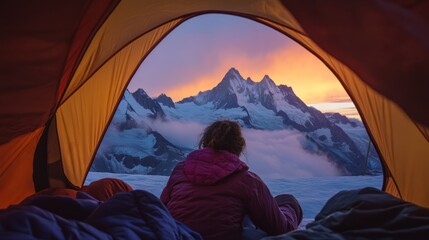 Person inside a tent at sunrise over mountains