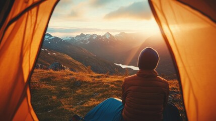 Person in tent overlooking mountain sunrise