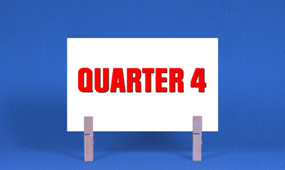 QUARTER 4 Symbol. Concept words QUARTER 4 on White Rectangle Paper Held by Wooden Clothespin Blue...