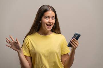 Fototapeta premium Excited young woman celebrating good news on her smartphone.