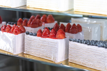 Delicious strawberry and blueberry cakes displayed in a bakery showcase