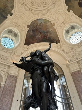 Dramatic bronze sculpture inside the Petit Palais museum in Paris with baroque ceiling and murals.
