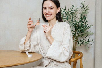 Woman taking vitamin supplement for beauty and health in a cozy setting