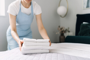 Hotel staff neatly arranging fresh towels in a modern hotel room