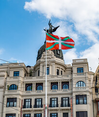 The Basque flag (Ikurriña) waves proudly in front of a historic building in Bilbao’s Casco...