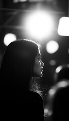 Silhouetted profile of a woman with glowing outlines, creating dramatic contrast against a dark background with bokeh lights.