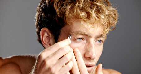Skincare, eyebrows and tweezers with man for grooming, hygiene or hair removal in studio. Cosmetic,...