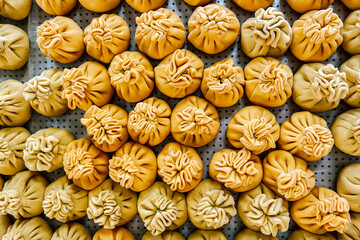 yellow dumplings neatly arranged on a tray in a bustling market during midday