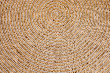 Fototapeta premium Intricate woven circular pattern displayed on a natural fiber rug in a cozy room setting