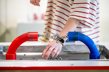 Child engaging with a hands-on science exhibit, demonstrating magnetic forces. Red and blue magnets attract metal pieces, showcasing educational fun and interactive learning