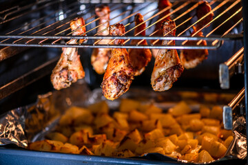 Juicy chicken drumsticks roasting on an oven rack, with golden baked potatoes beneath. Perfectly cooked meal showcasing a delicious combination of flavors and textures