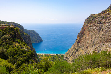 Fototapeta premium Scenic turquoise bay with beach nestled between steep green cliffs, view from mountain trail