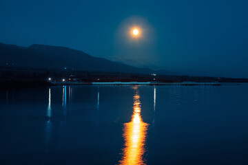 Lake and mountains landscape with moon reflecting in the water