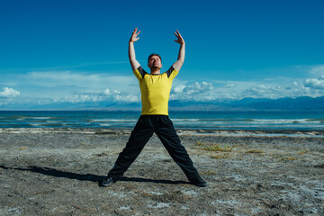 Young man fitness training on lake shore on summer day