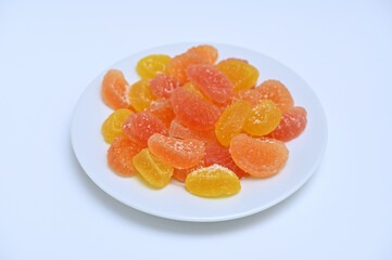 plate with bright marmalade on white background close-up