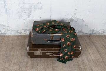 Vintage old classic travel leather suitcase circa 1940-60s with a vintage scarf. Travel luggage concept. Retro brown suitcase on a white wall background.