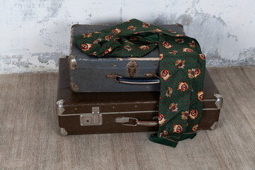 Vintage old classic travel leather suitcase circa 1940-60s with a vintage scarf. Travel luggage concept. Retro brown suitcase on a white wall background.