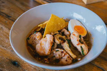 Delicious Shrimp Dish with Egg, Crispy Tortilla and Flavorful Broth in a Bowl on Rustic Wooden Table