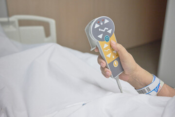 Hospital patient’s hand using remote control to adjust the position of an articulated bed