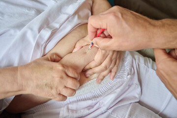 Close-up of male hands injecting anticoagulant medicine into a woman’s abdominal area using a...