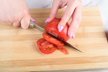 Cutting a tomato into pieces with a knife.