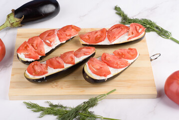 Eggplant halves with sauce and tomatoes for baking.
