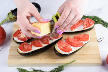 Grating cheese on eggplant with sour cream sauce and tomatoes.