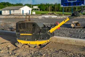 Vibratory plate compactor on a construction site on compacted stone surface.	