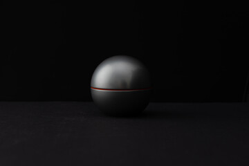 Perfume in a round bottle and a bird feather on a dark background