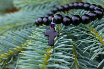 Black beads bracelet with a cross on a fir tree branch
